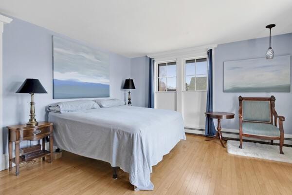 bedroom featuring light wood-style floors and a baseboard heating unit