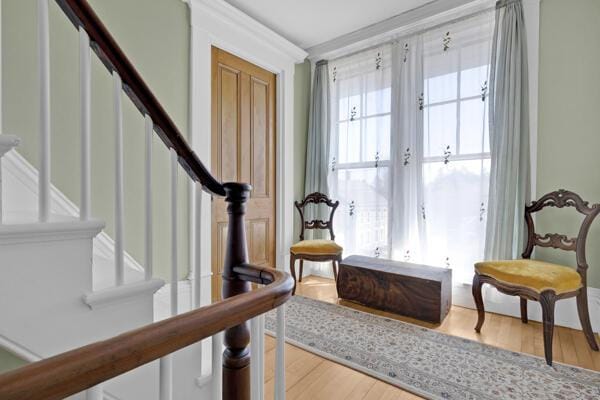 living area featuring stairs, crown molding, and wood finished floors