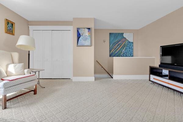 living area featuring baseboards, carpet, and an upstairs landing
