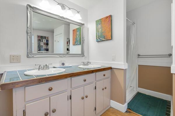 bathroom with double vanity, a sink, baseboards, and curtained shower