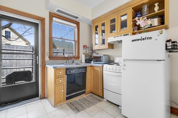 kitchen featuring a sink, white appliances, light countertops, under cabinet range hood, and glass insert cabinets