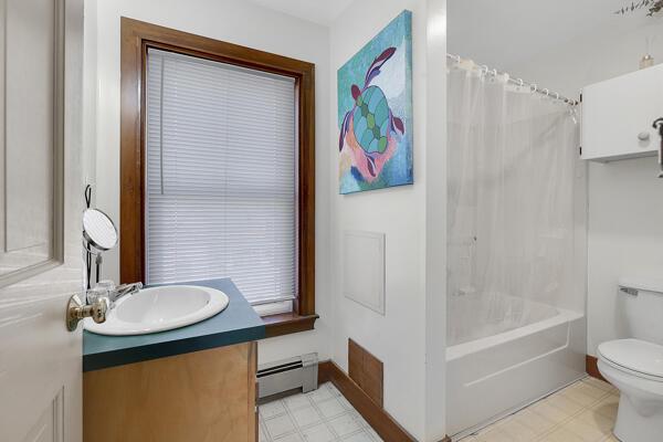 full bath with vanity, shower / bath combo with shower curtain, toilet, baseboard heating, and tile patterned floors