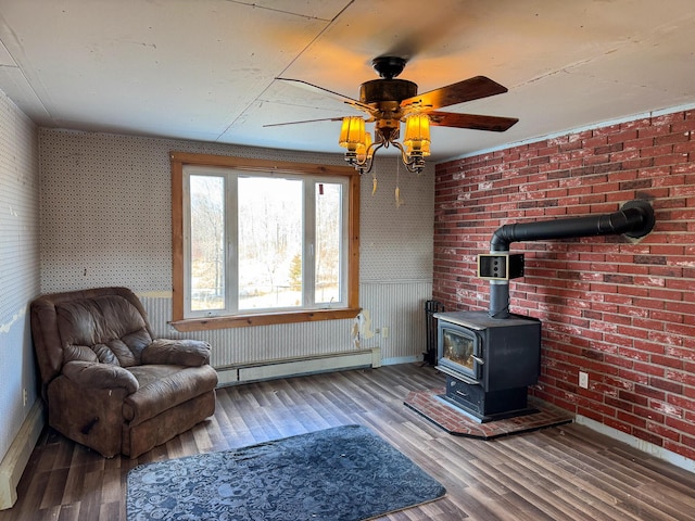 201 Mcburnie Rd, Presque Isle, ME 04769 - unfurnished room featuring ceiling fan, a wood stove, wood finished floors, a baseboard heating unit, and baseboards