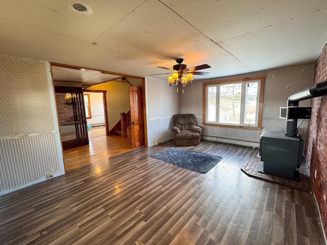 201 Mcburnie Rd, Presque Isle, ME 04769 - unfurnished room featuring a ceiling fan, a wood stove, stairs, a baseboard radiator, and wood finished floors