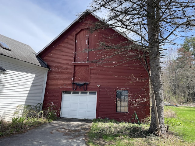view of property exterior featuring a barn, an outdoor structure, asphalt driveway, and a garage