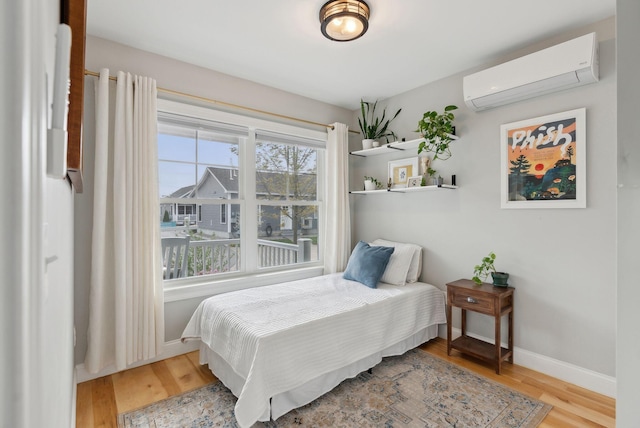 66 Evans St Unit 12, South Portland, ME 04106 - bedroom with a wall mounted air conditioner, wood finished floors, and baseboards