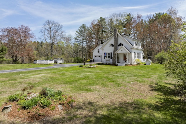 294 E Pond Rd, Jefferson, ME 04348 - view of side of home featuring a chimney, asphalt driveway, a garage, and a lawn