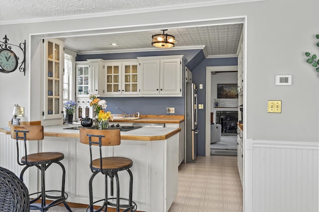 294 E Pond Rd, Jefferson, ME 04348 - kitchen featuring a peninsula, a kitchen breakfast bar, ornamental molding, white cabinetry, and light countertops