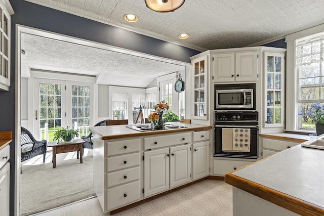 294 E Pond Rd, Jefferson, ME 04348 - kitchen featuring black oven, stainless steel microwave, white cabinets, glass insert cabinets, and an ornate ceiling