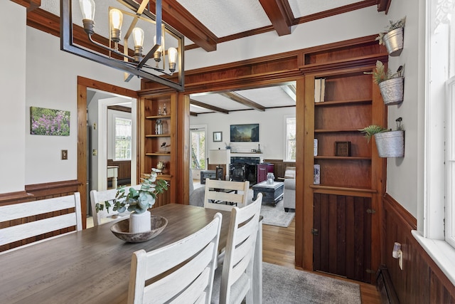 294 E Pond Rd, Jefferson, ME 04348 - dining room featuring a fireplace, beamed ceiling, wood finished floors, wainscoting, and a chandelier