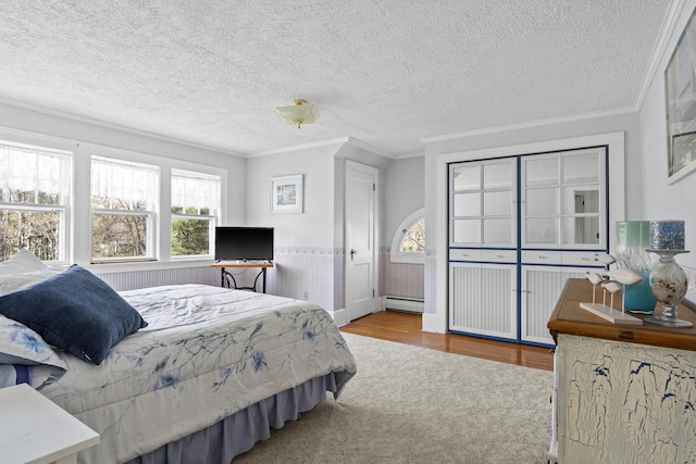 294 E Pond Rd, Jefferson, ME 04348 - carpeted bedroom with crown molding, a wainscoted wall, a baseboard radiator, a textured ceiling, and wood finished floors