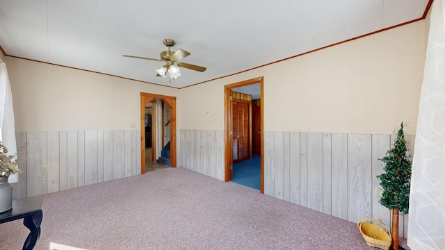 spare room with ornamental molding, ceiling fan, wainscoting, and carpet floors