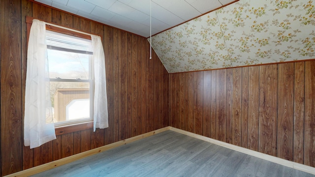 bonus room featuring wood finished floors, wooden walls, and baseboards