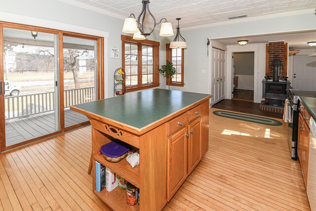 257 S Rumford Rd, Rumford, ME 04276 - kitchen with light wood-type flooring, dark countertops, a wood stove, decorative light fixtures, and open shelves