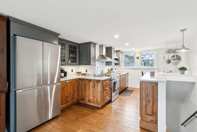 1081 Kings Hwy, Kennebunkport, ME 04046 - kitchen featuring stainless steel appliances, wall chimney range hood, light wood-style floors, glass insert cabinets, and a sink