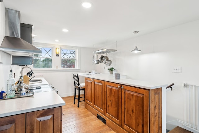 1081 Kings Hwy, Kennebunkport, ME 04046 - kitchen featuring wall chimney range hood, baseboards, light wood-style floors, light countertops, and brown cabinetry
