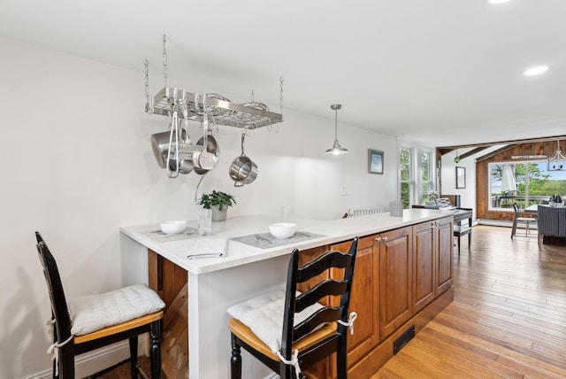 1081 Kings Hwy, Kennebunkport, ME 04046 - kitchen with light wood-style flooring, a peninsula, recessed lighting, brown cabinetry, and a kitchen bar