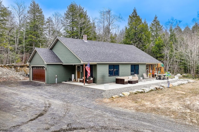 single story home featuring a patio area, a garage, a chimney, dirt driveway, and an outdoor hangout area
