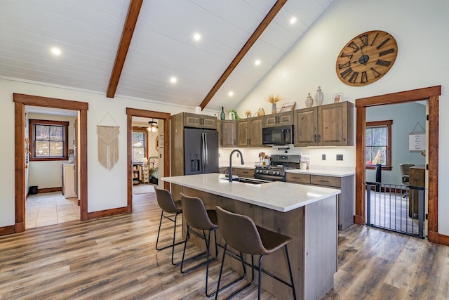 kitchen with light wood-type flooring, a sink, beam ceiling, and appliances with stainless steel finishes