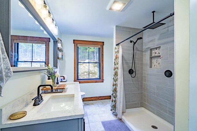 bathroom with a stall shower, double vanity, a sink, and tile patterned floors