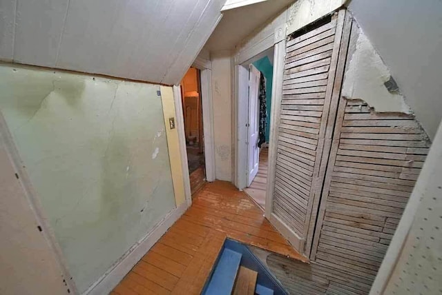 corridor featuring light wood finished floors and lofted ceiling