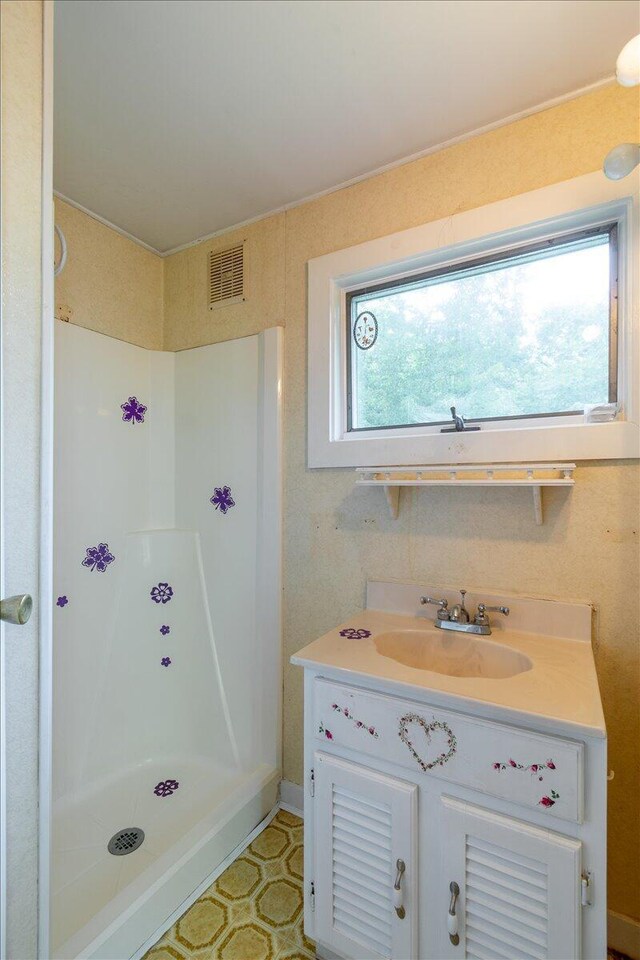 full bath featuring a stall shower, vanity, and visible vents
