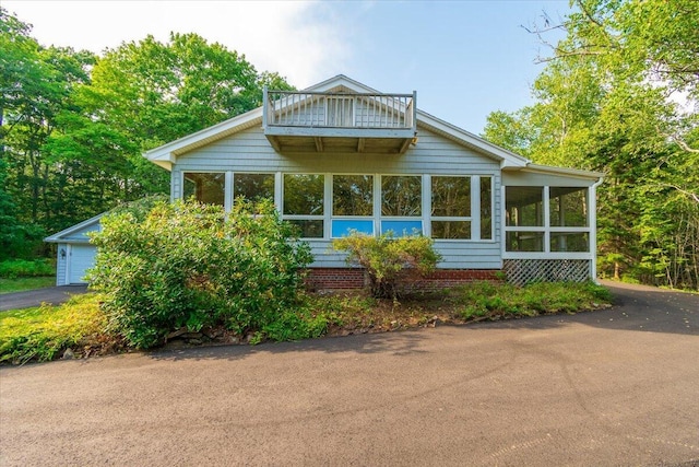view of front facade with a sunroom, a garage, aphalt driveway, and a balcony