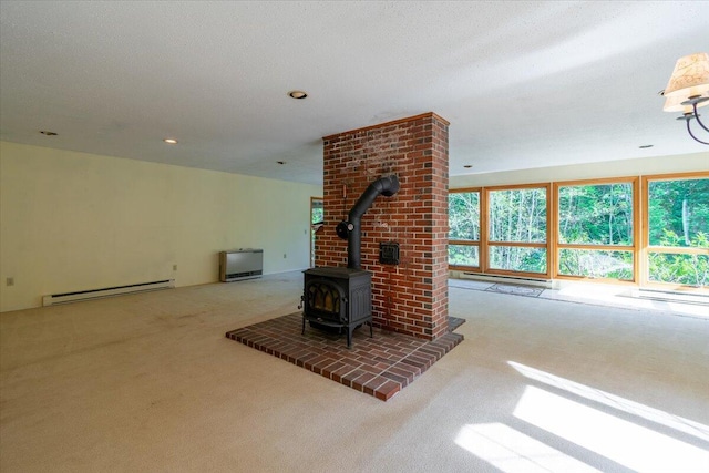unfurnished living room with baseboard heating, carpet flooring, and a wood stove