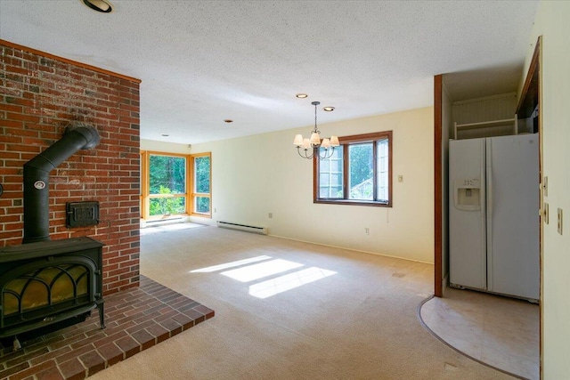 unfurnished living room featuring a wood stove, carpet, a baseboard heating unit, and a healthy amount of sunlight
