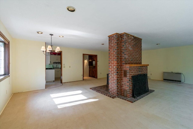 unfurnished living room featuring recessed lighting, a brick fireplace, light colored carpet, and an inviting chandelier