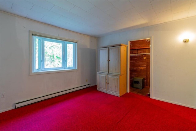 unfurnished bedroom featuring a closet, a walk in closet, a baseboard radiator, and carpet floors
