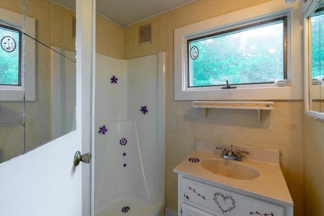 bathroom with vanity, visible vents, and walk in shower