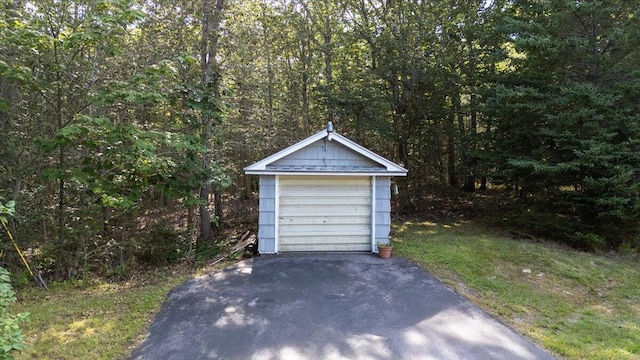detached garage featuring a wooded view and driveway