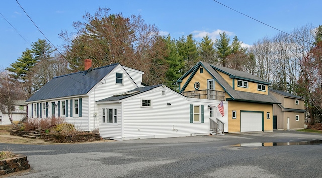 view of front of property with an attached garage, entry steps, a chimney, and aphalt driveway