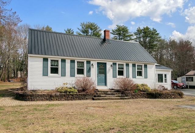 view of front of home featuring a chimney, a front lawn, entry steps, and metal roof