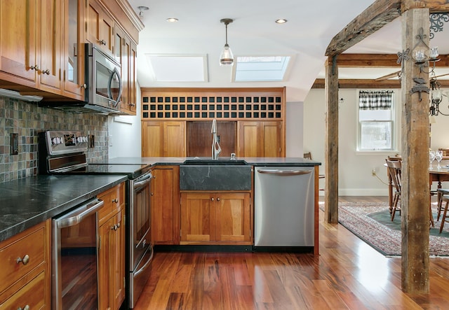 kitchen featuring a skylight, brown cabinetry, wine cooler, and appliances with stainless steel finishes