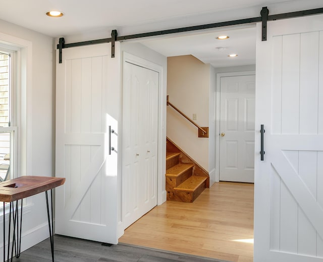 entrance foyer featuring a barn door, recessed lighting, stairs, and light wood-style flooring