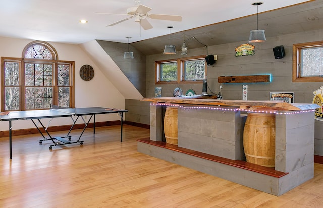 bar with vaulted ceiling, wood finished floors, a ceiling fan, and baseboards