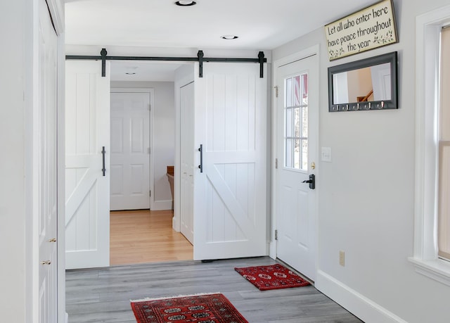 foyer featuring a barn door, wood finished floors, baseboards, and recessed lighting