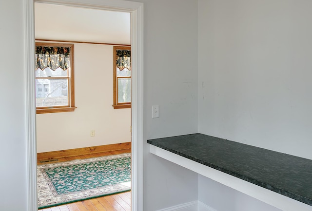 corridor featuring wood finished floors and baseboards