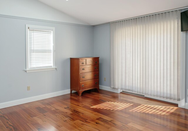 empty room with lofted ceiling, wood finished floors, and baseboards