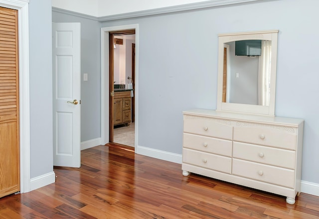 bedroom with wood finished floors, a closet, baseboards, and connected bathroom