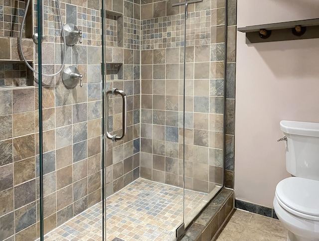 bathroom with toilet, tile patterned floors, and a stall shower