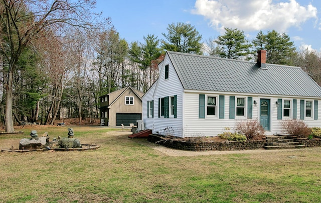 rear view of property featuring a lawn, a chimney, metal roof, and a garage