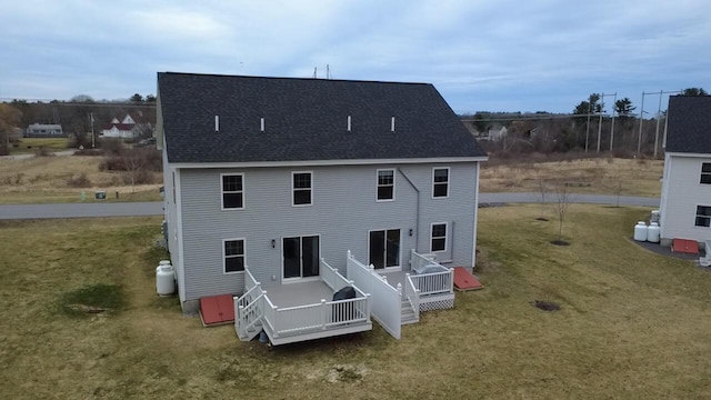 back of property featuring a deck, a lawn, and roof with shingles