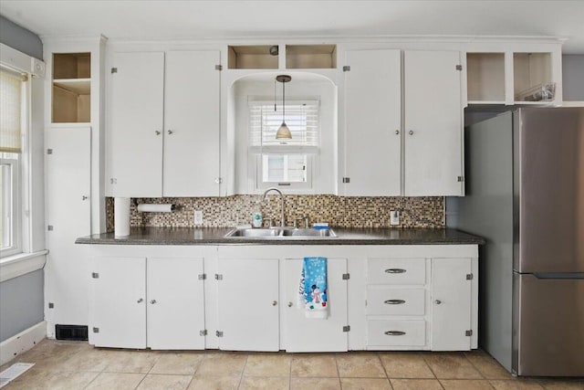 kitchen with a sink, freestanding refrigerator, decorative backsplash, and open shelves