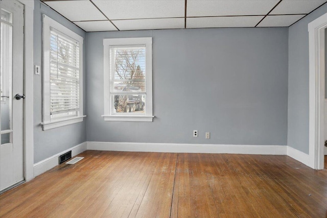 spare room with a paneled ceiling, hardwood / wood-style flooring, baseboards, and visible vents