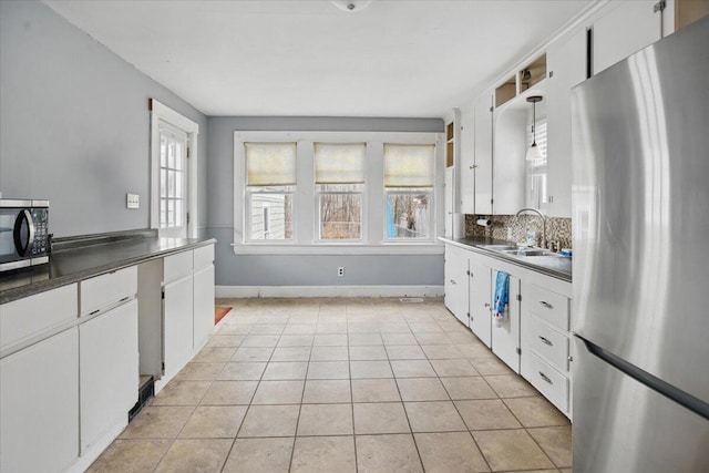 kitchen with freestanding refrigerator, dark countertops, light tile patterned floors, and plenty of natural light