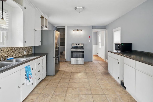 kitchen with tasteful backsplash, white cabinetry, dark countertops, appliances with stainless steel finishes, and a sink