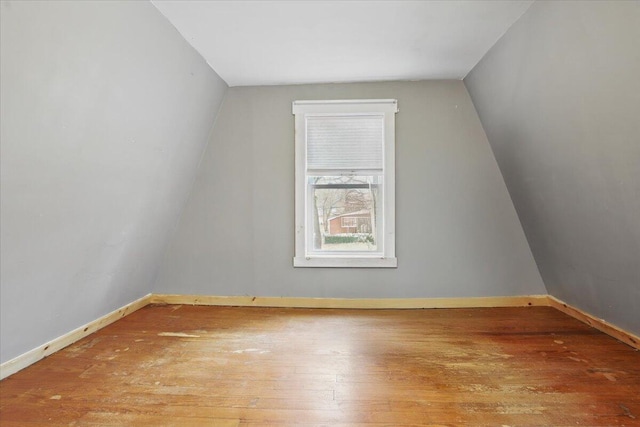 additional living space with hardwood / wood-style floors, baseboards, and vaulted ceiling